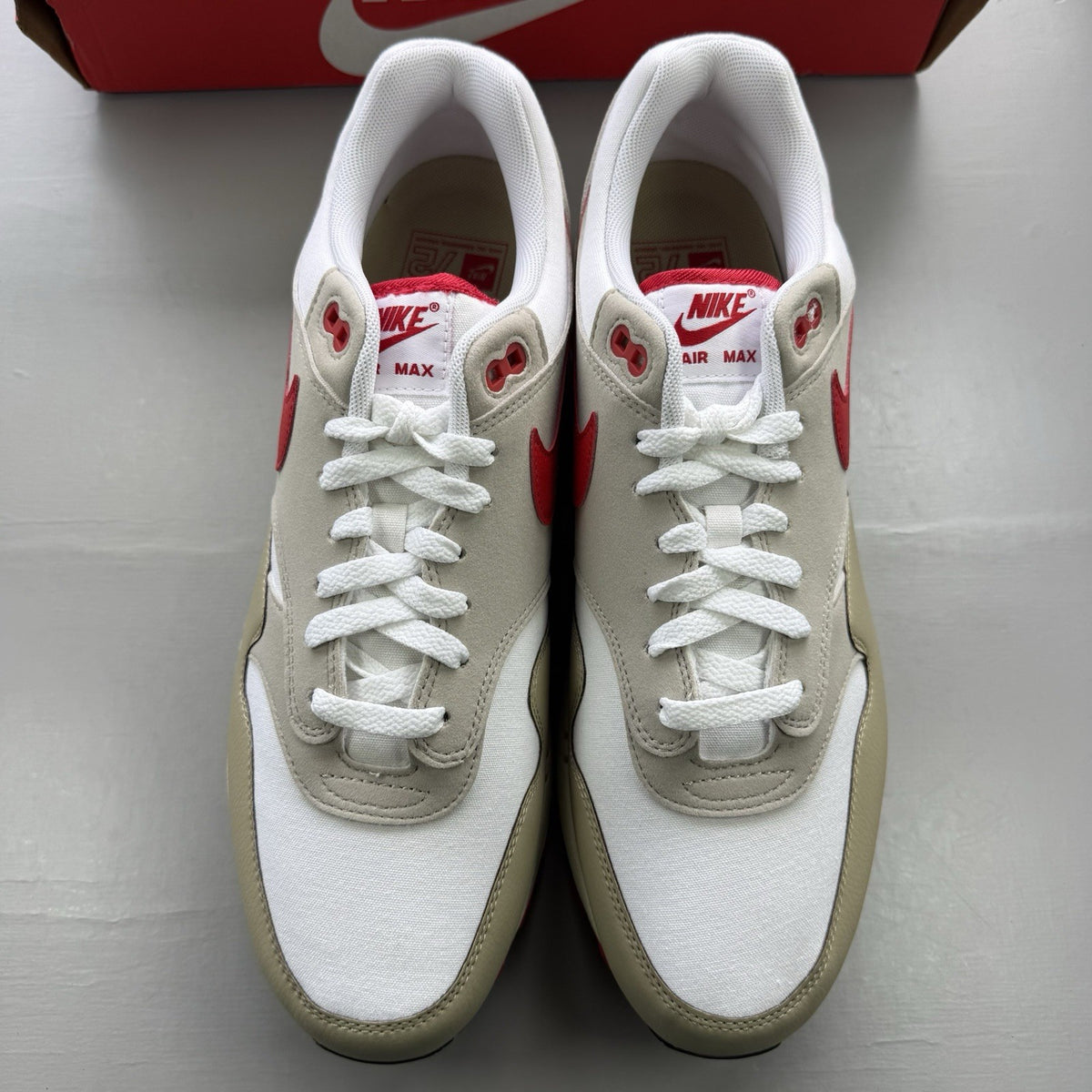 Nike Air Max 1 trainers white with university red accents and cream detailing.