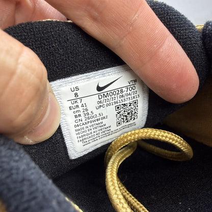 Nike Air Max 97 gold trainers with white and black accents, featuring a sleek design.