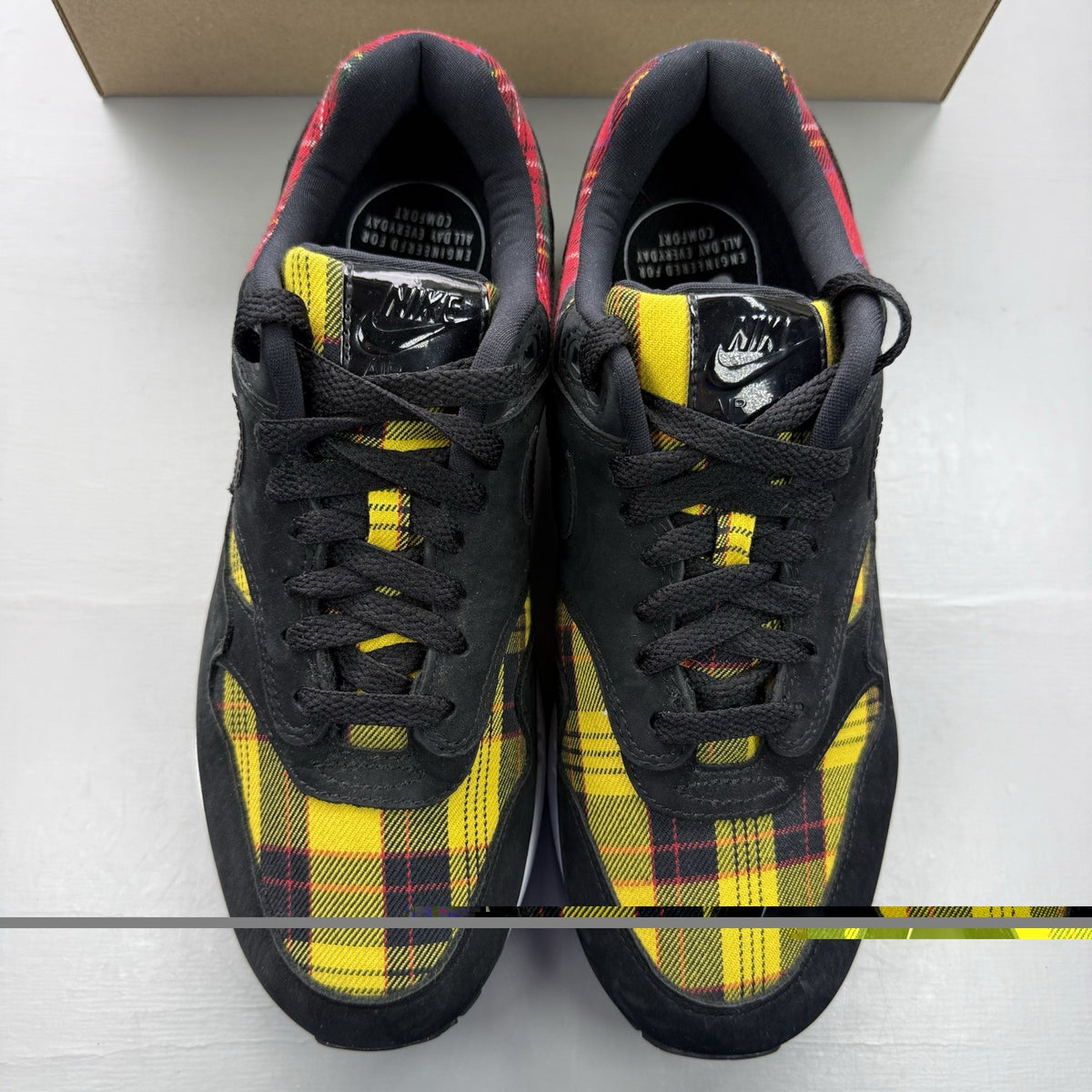 Nike Air Max 1 SE trainers black with tartan pattern and yellow accents.