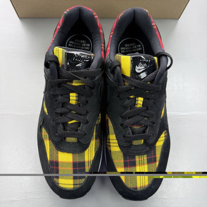 Nike Air Max 1 SE trainers black with tartan pattern and yellow accents.