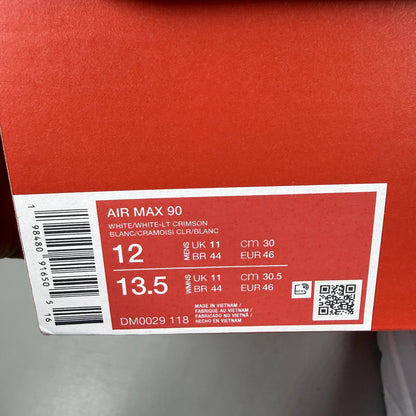 Nike Air Max 90 white trainers with light crimson accents and signature swoosh logo.
