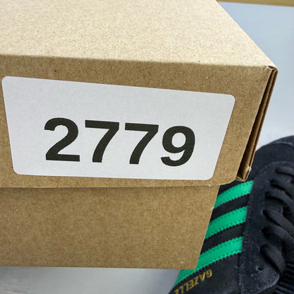 Adidas black Gazelle trainers with green accents and classic logo detailing.