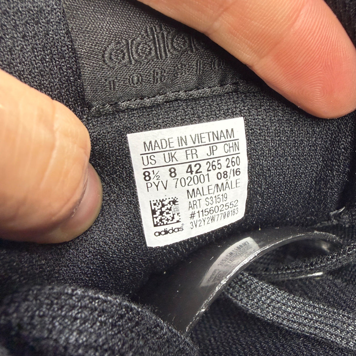 Adidas black trainers with iridescent accents and signature logo on tongue.