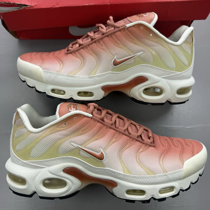Nike Air Max Plus TN white trainers with peach accents and signature swoosh logo.