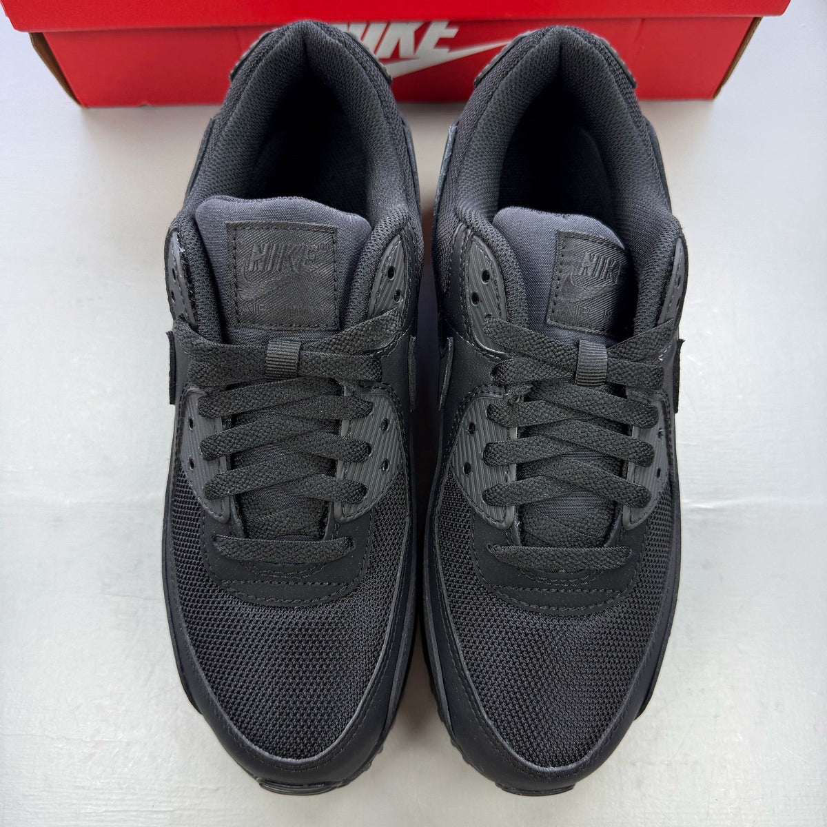 Nike Air Max 90 trainers black with signature logo and sleek design.