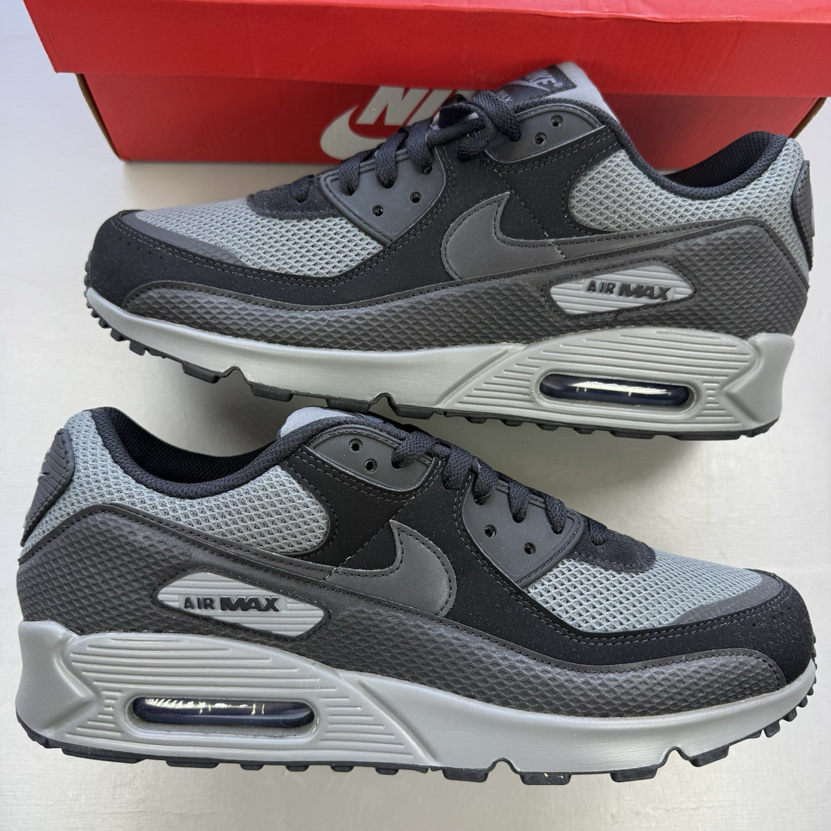Nike Air Max 90 black trainers with grey accents and iconic logo detail.