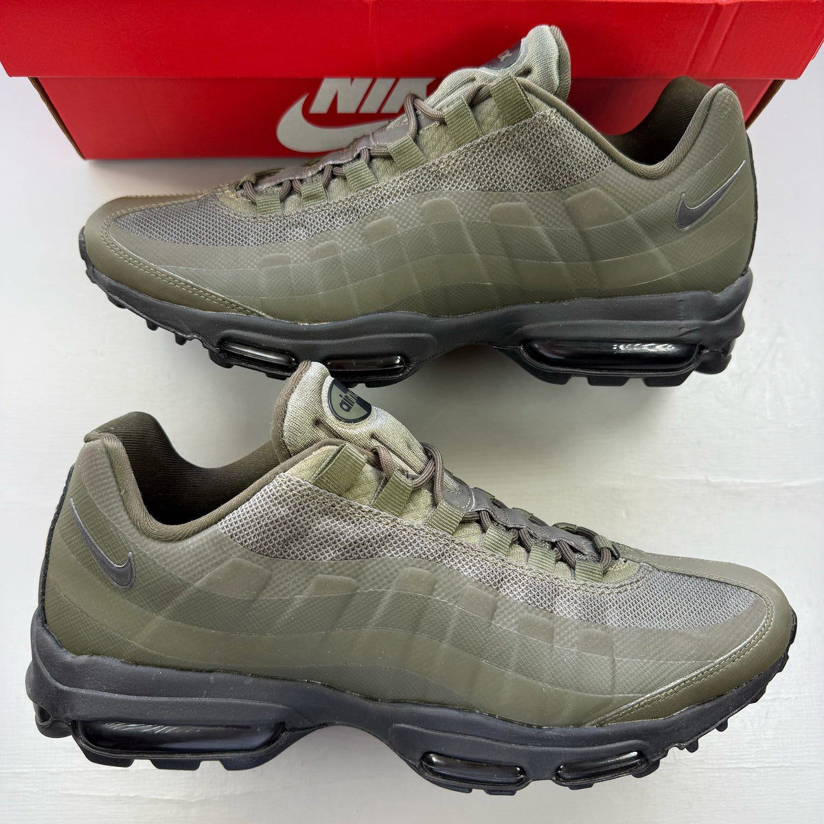 Nike Air Max 95 Ultra green trainers with black accents and logo details.