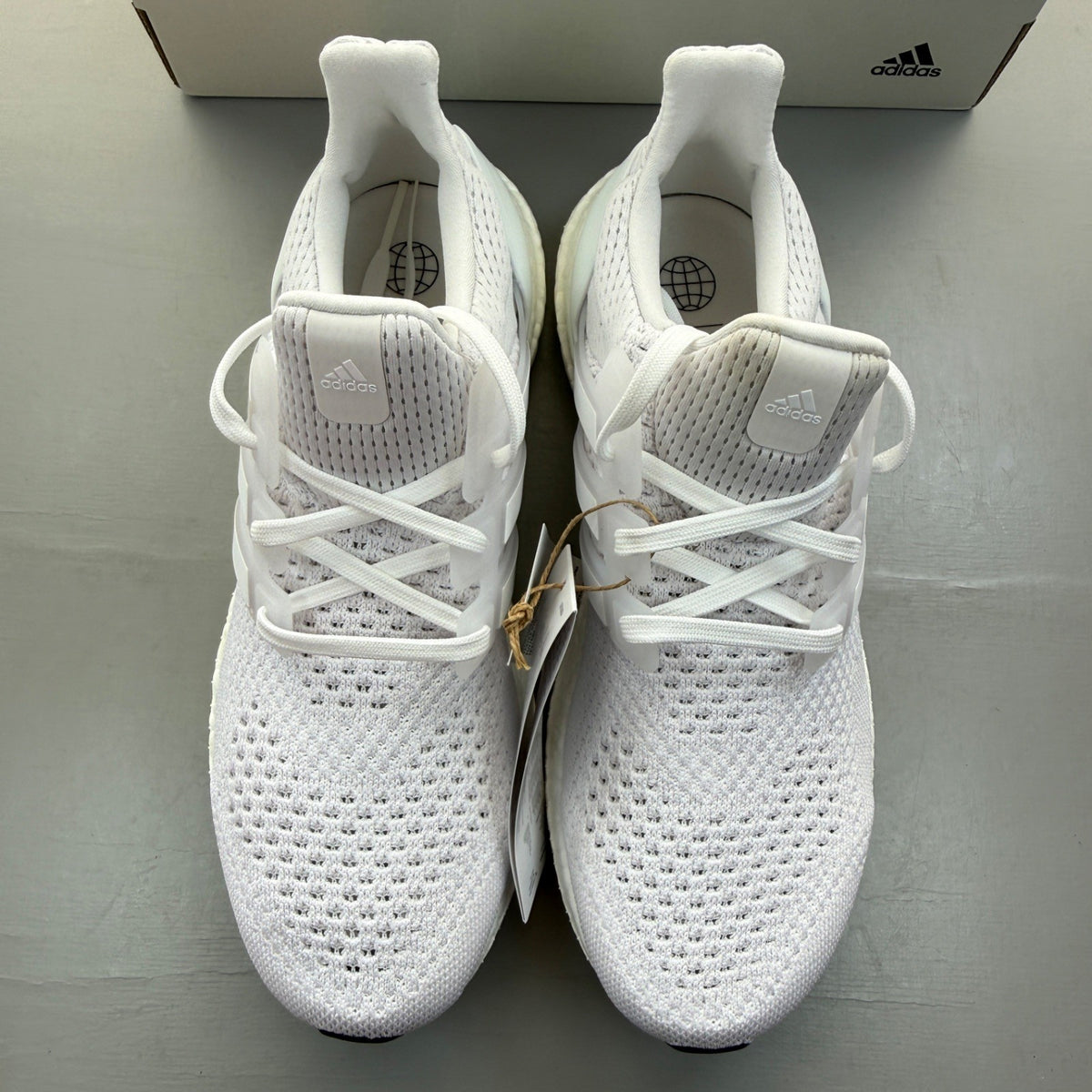 Adidas Ultra Boost 1.0 white running trainers with textured knit upper and signature three stripes.