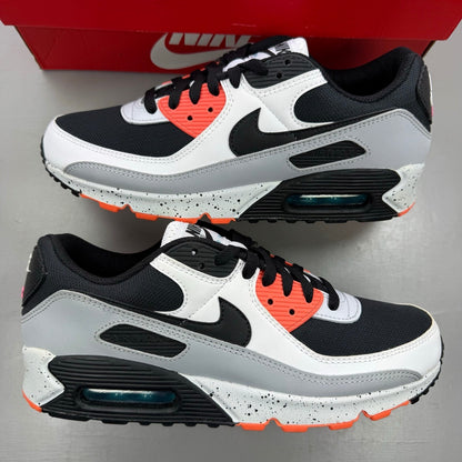 Nike Air Max 90 black trainers with turf orange and white accents, featuring logo details.