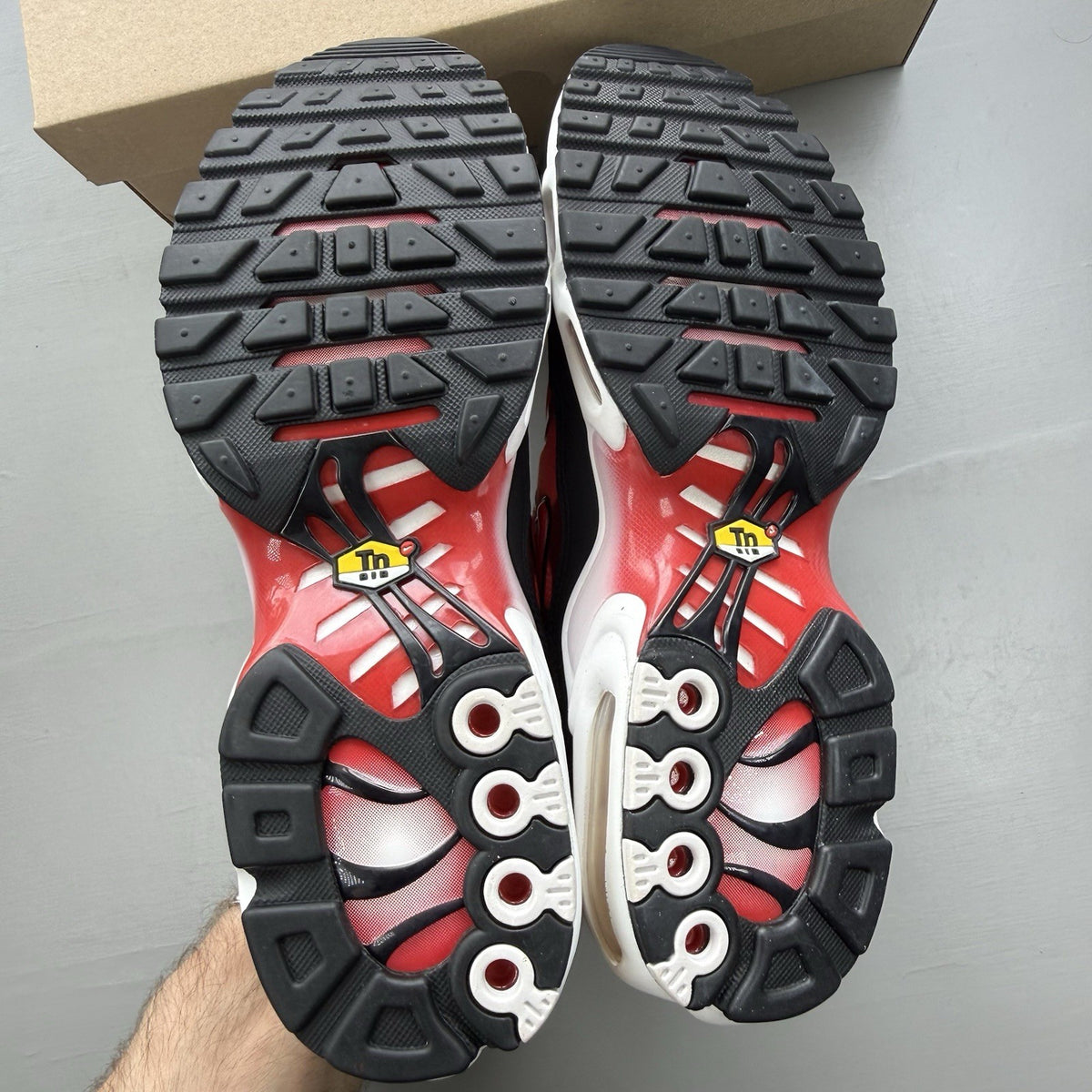 Nike Air Max Plus TN white trainers with black and university red accents, mesh material.