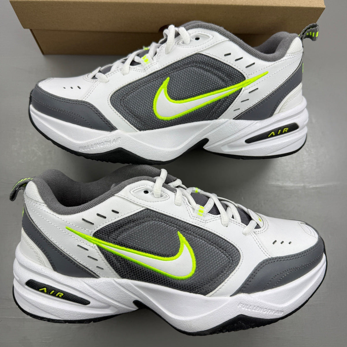 Nike Air Monarch IV white trainers with cool grey and green accents, featuring logo detail.