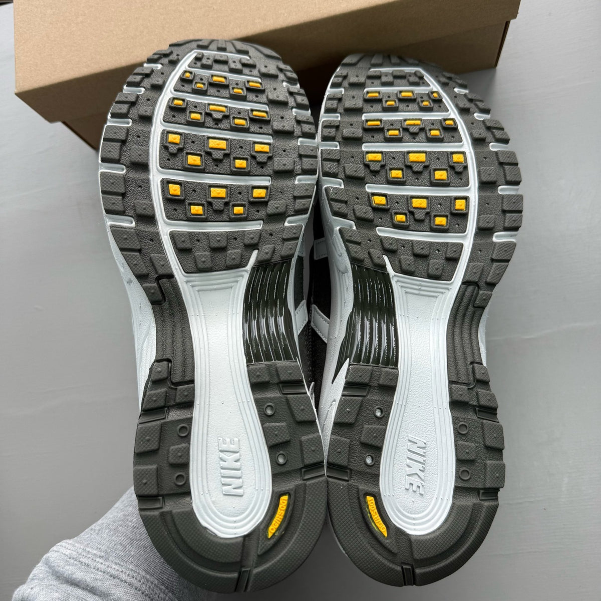 Nike grey P-6000 trainers with laser orange accents and mesh material.
