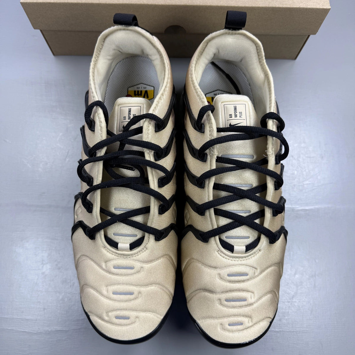 Nike beige trainers with black accents and Air cushioning design.