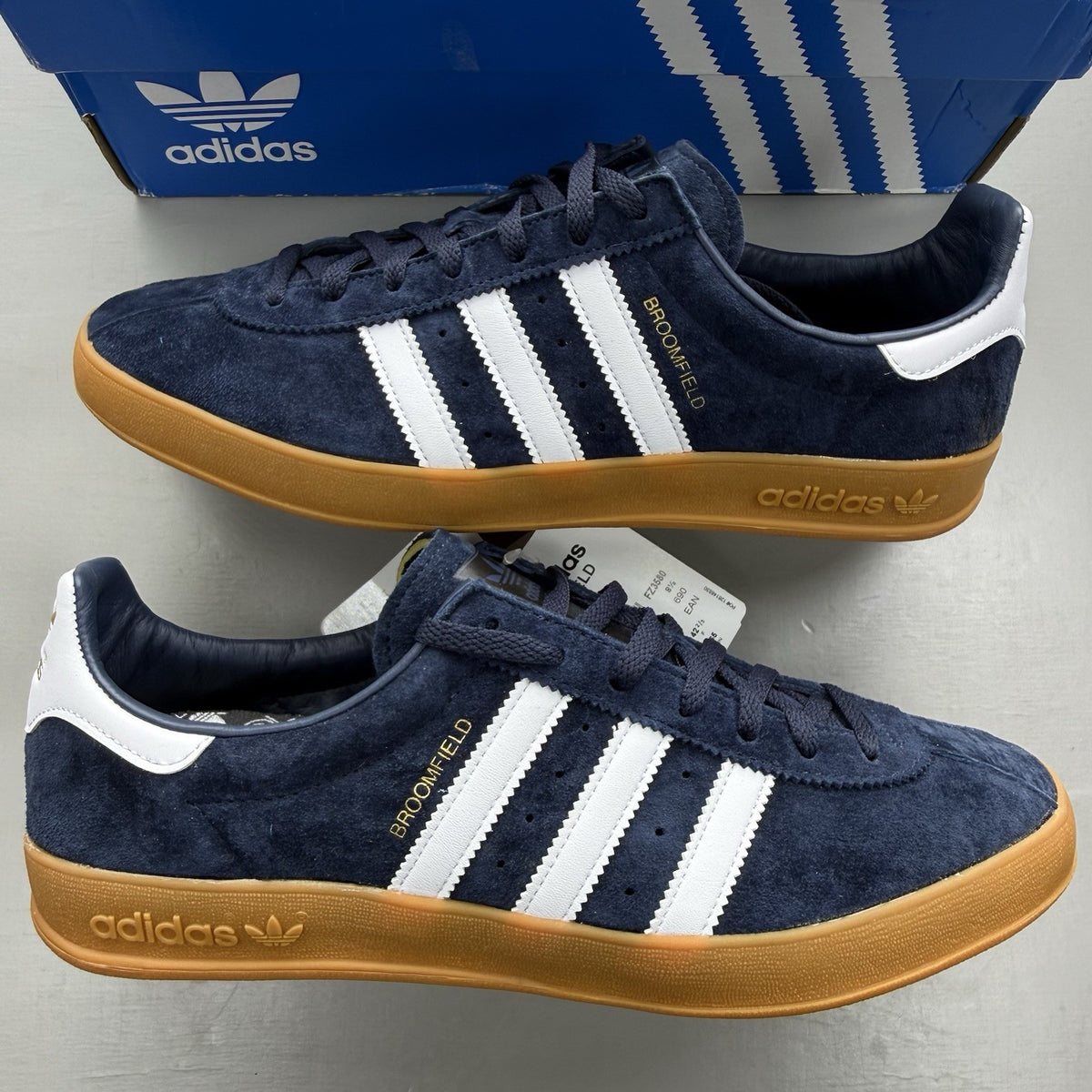 Adidas blue trainers with white and gum sole, featuring gold accents and logo.