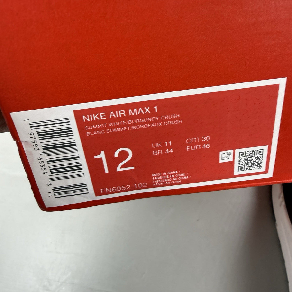Nike Air Max 1 white trainers with burgundy and red accents, featuring logo details.