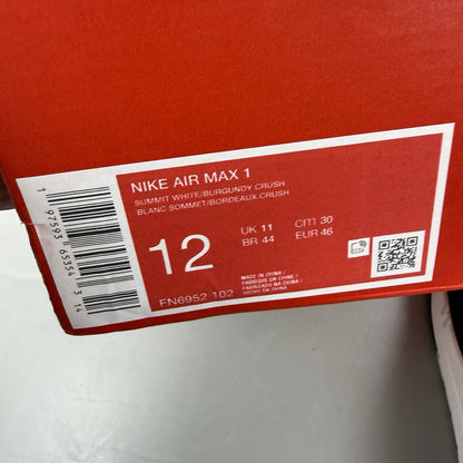 Nike Air Max 1 white trainers with burgundy and red accents, featuring logo details.