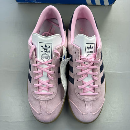 Adidas pink trainers with gum sole, featuring iconic three stripes logo.