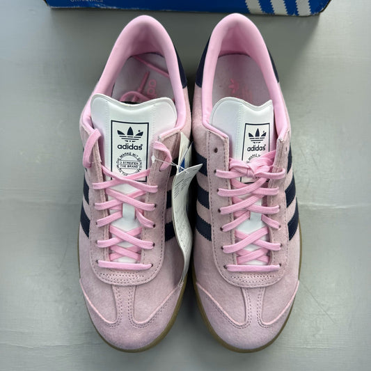 Adidas pink trainers with gum sole, featuring iconic three stripes logo.