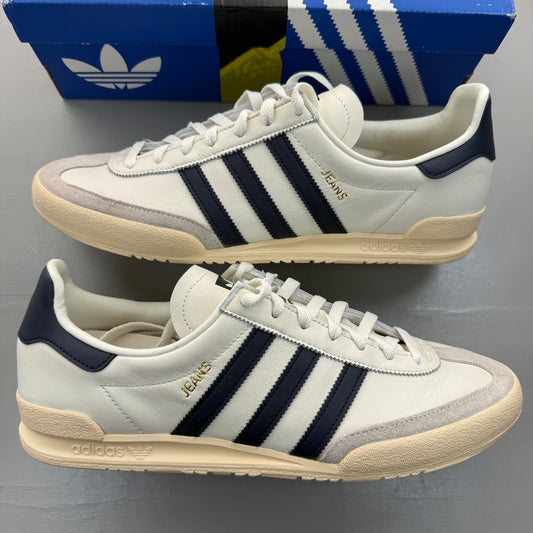 Adidas white trainers with navy accents and leather detailing, featuring iconic logo.