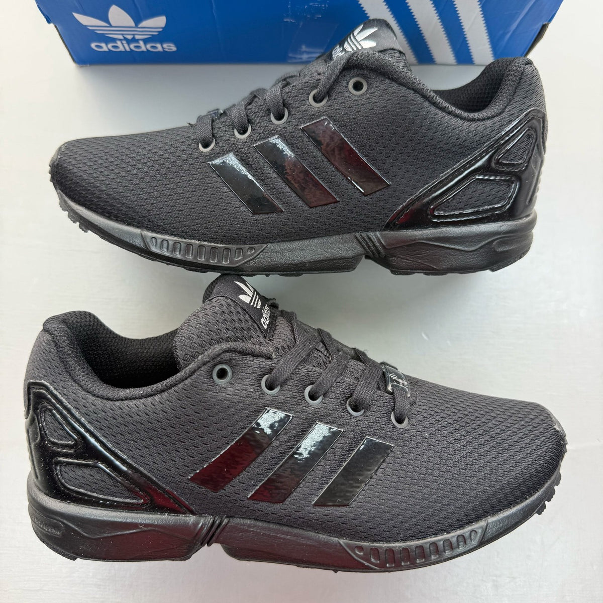 Adidas black trainers with sleek design and logo detail, perfect for kids.