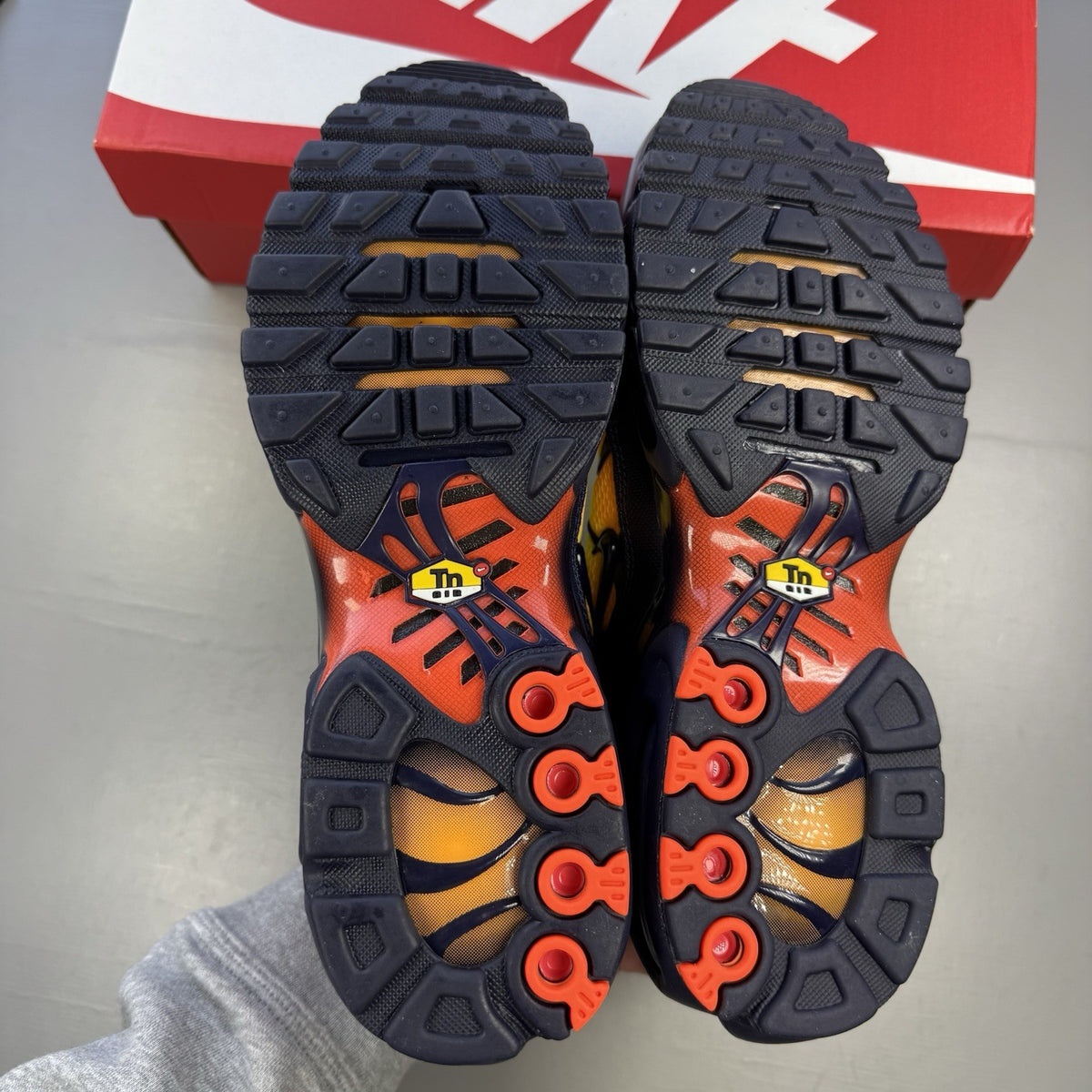 Nike Air Max Plus TN yellow trainers with orange accents and signature swoosh logo.