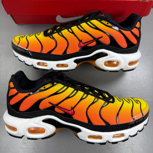 Nike running shoes sunset orange with black accents and distinctive Air Max Plus design.