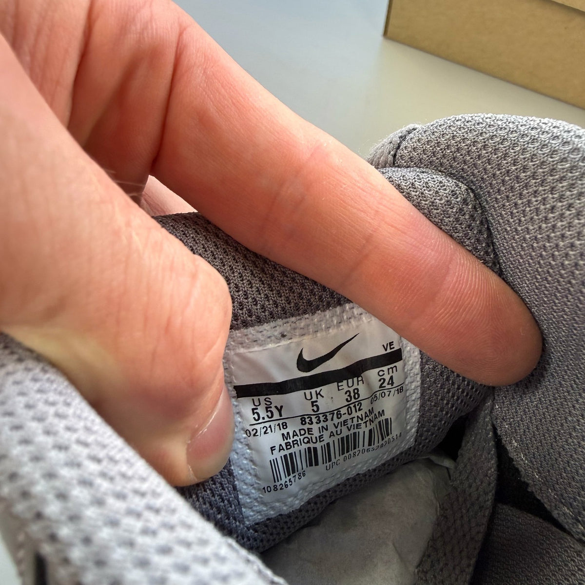 Nike Air Max 90 grey trainers with white accents and logo detail.