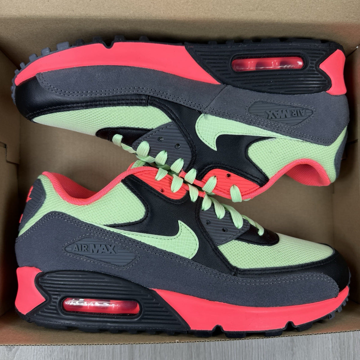 Nike Air Max 90 Essential green trainers with signature swoosh logo and mesh detailing.