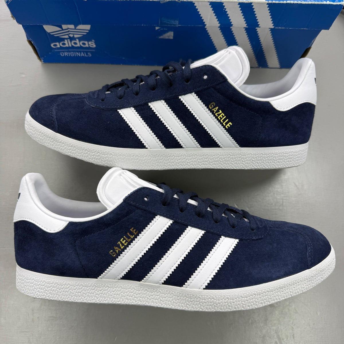 Adidas blue suede trainers with white stripes and logo detail.