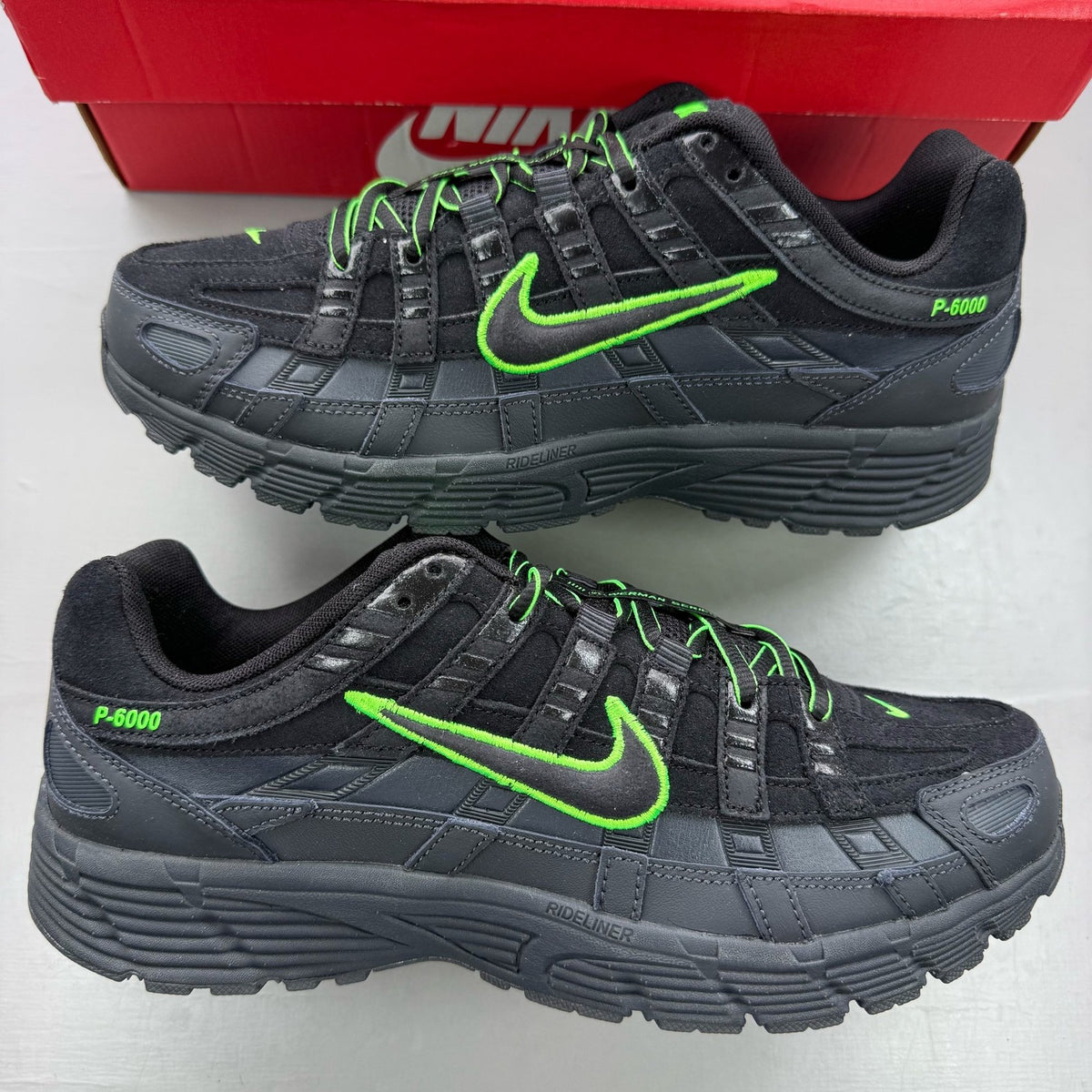 Nike P-6000 black trainers with green accents and mesh panels, 100% authentic.