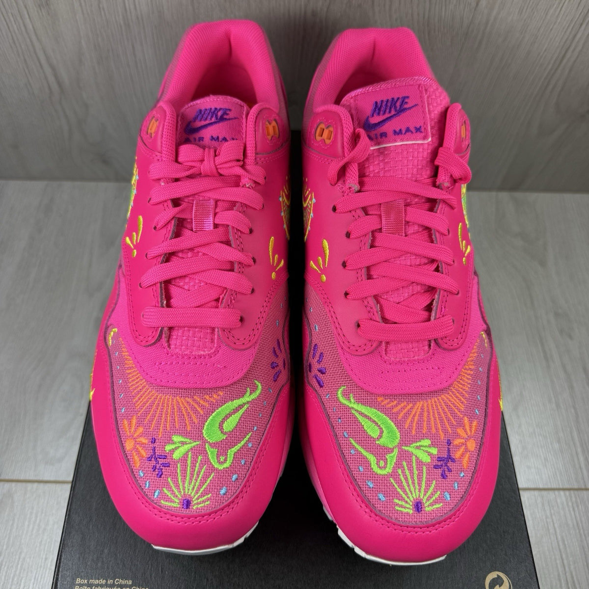 Nike Air Max 1 PRM trainers pink with Día De Muertos pattern and white accents.