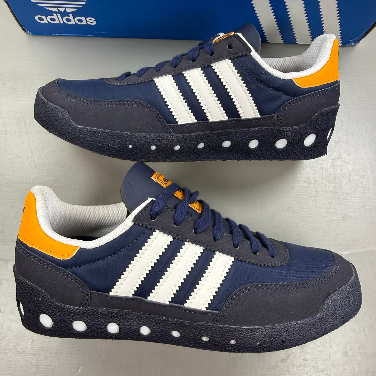 Adidas blue kids trainers with white and orange accents, featuring logo detail.