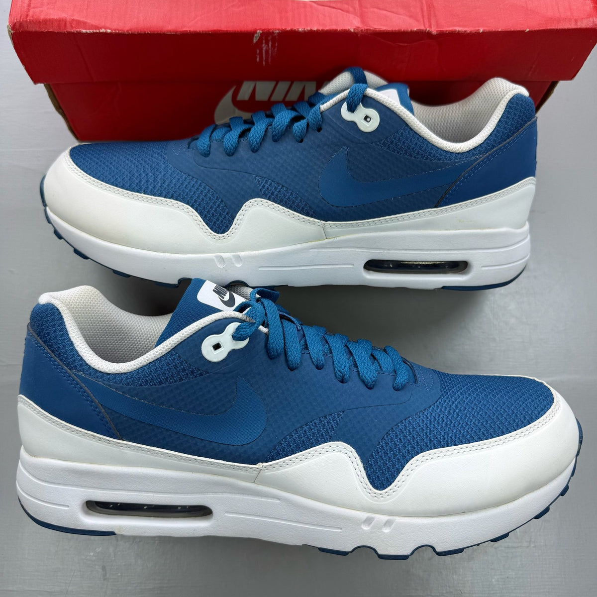 Nike Air Max 1 blue trainers with essential design and logo detail.