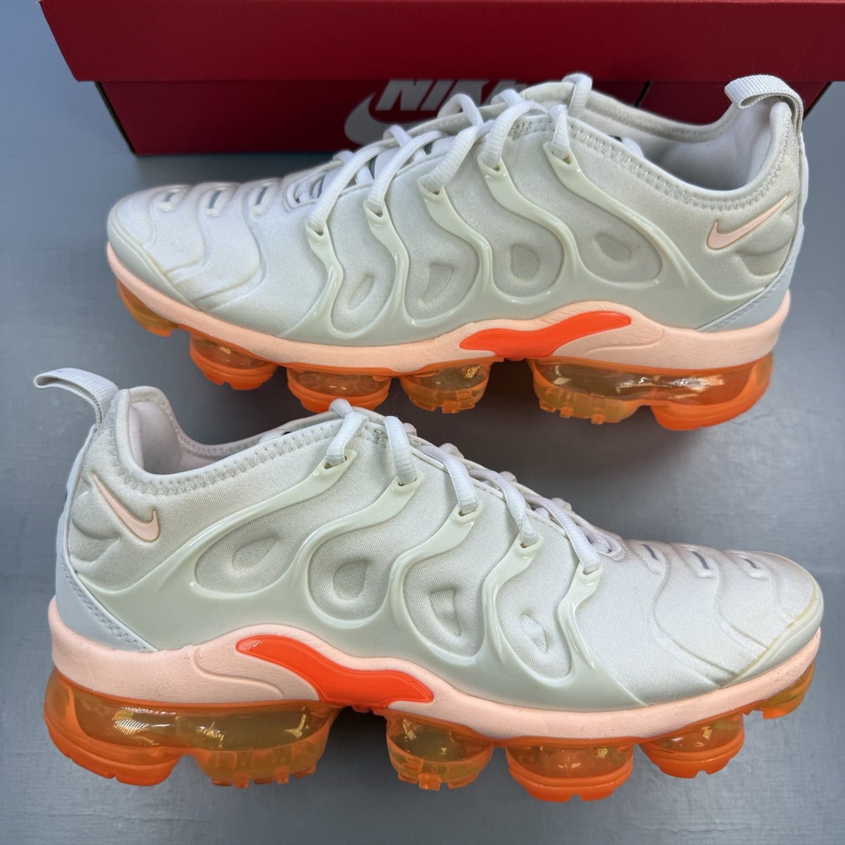 Nike Air VaporMax Plus beige trainers with Phantom Orange accents and distinctive logo.