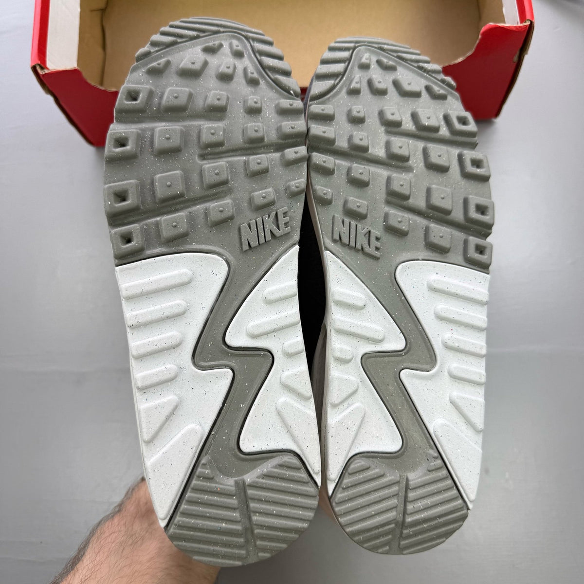 Nike Air Max 90 PRM grey trainers with white accents and distinctive logo details.