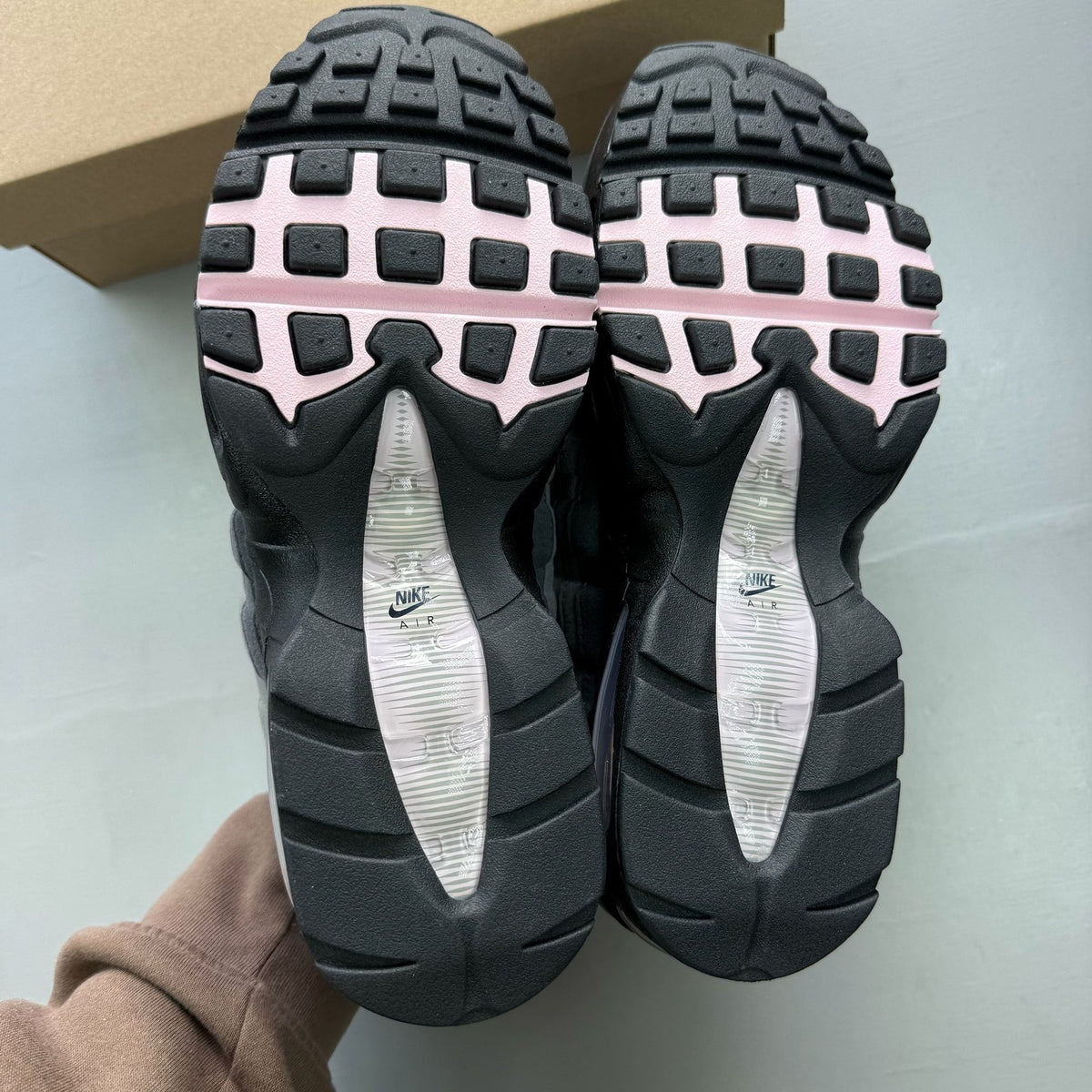 Nike Air Max 95 grey trainers with pink foam accents and black detailing.