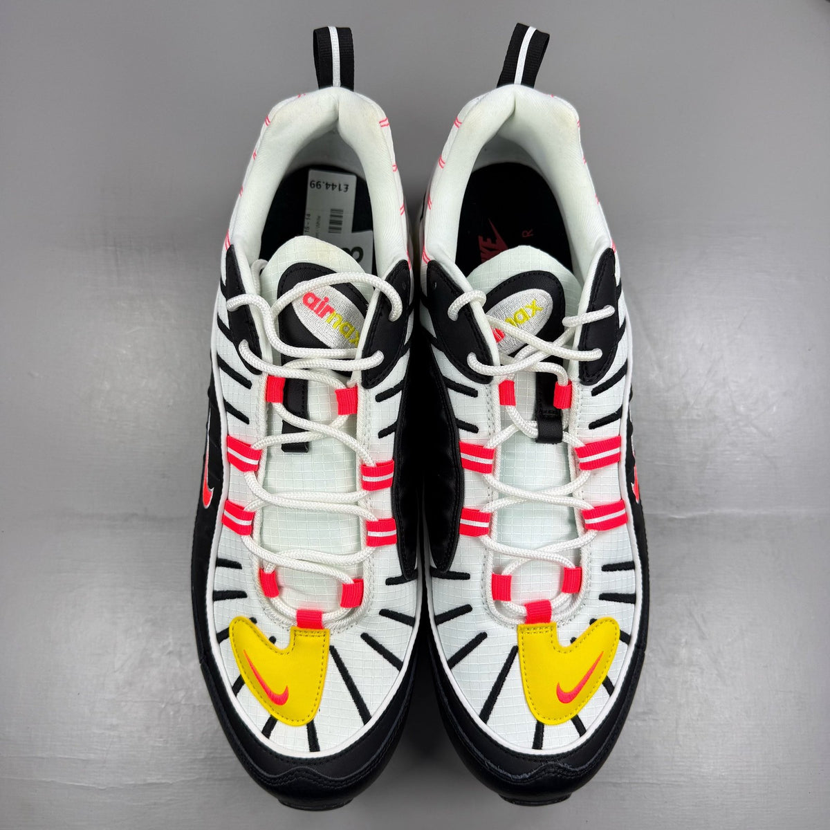 Nike Air Max 98 white trainers with black and yellow accents, featuring a sleek design.
