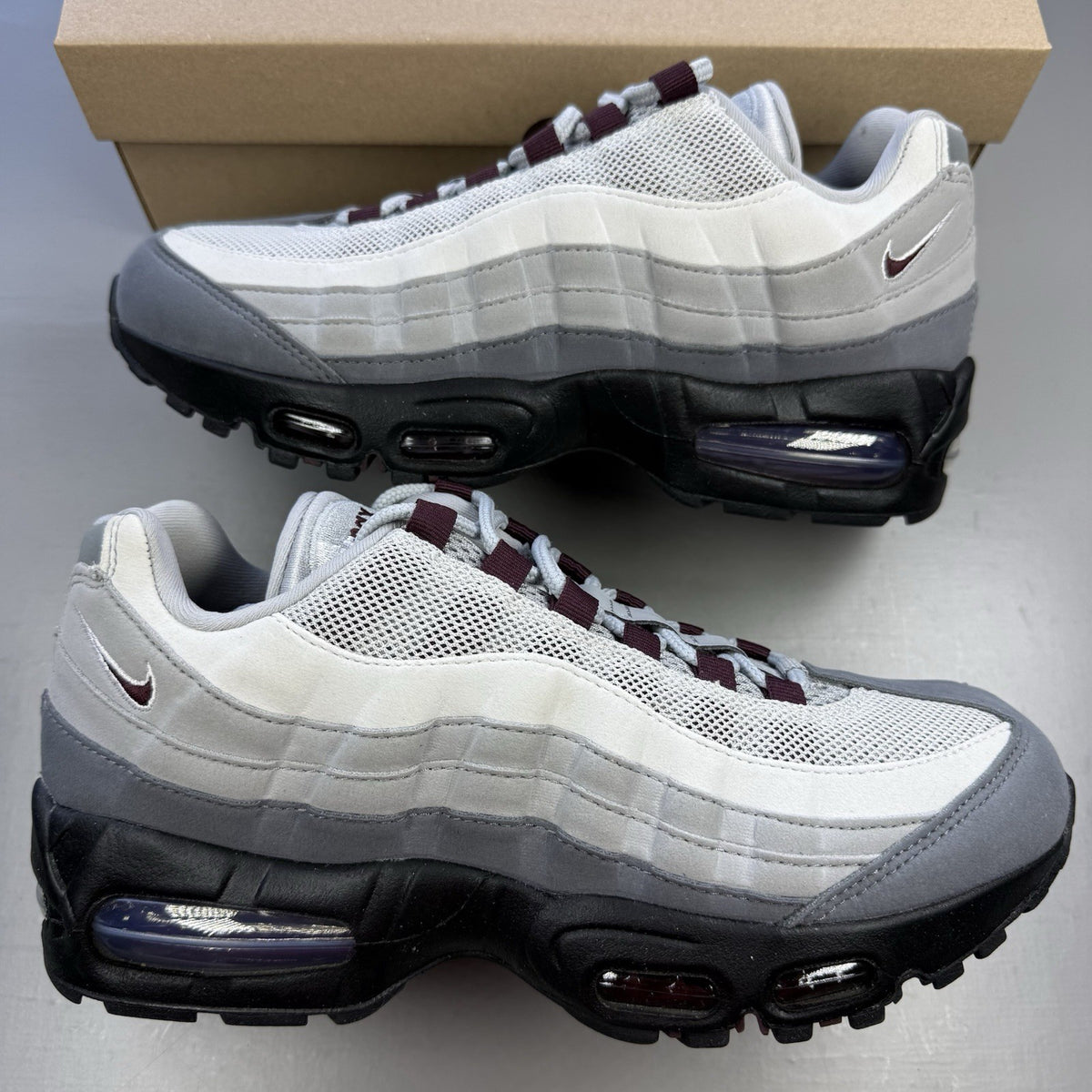 Nike Air Max 95 OG Big Bubble grey sneakers with burgundy accents and visible air cushioning.