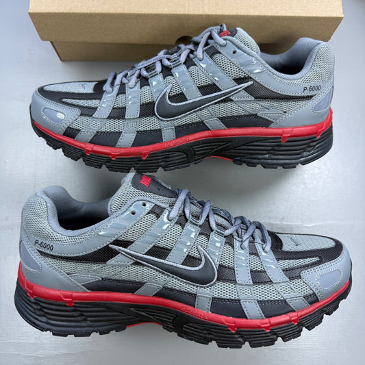 Nike grey trainers with red accents and black detailing, featuring a sleek design.