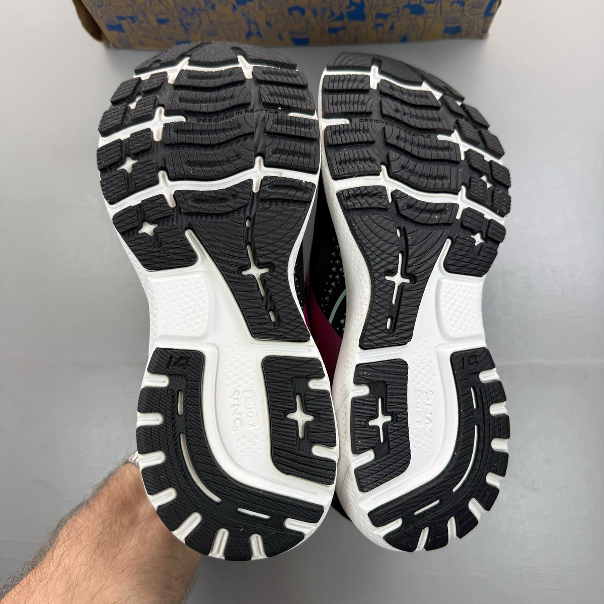 Brooks black trainers with white and pink accents, featuring logo and breathable mesh material.