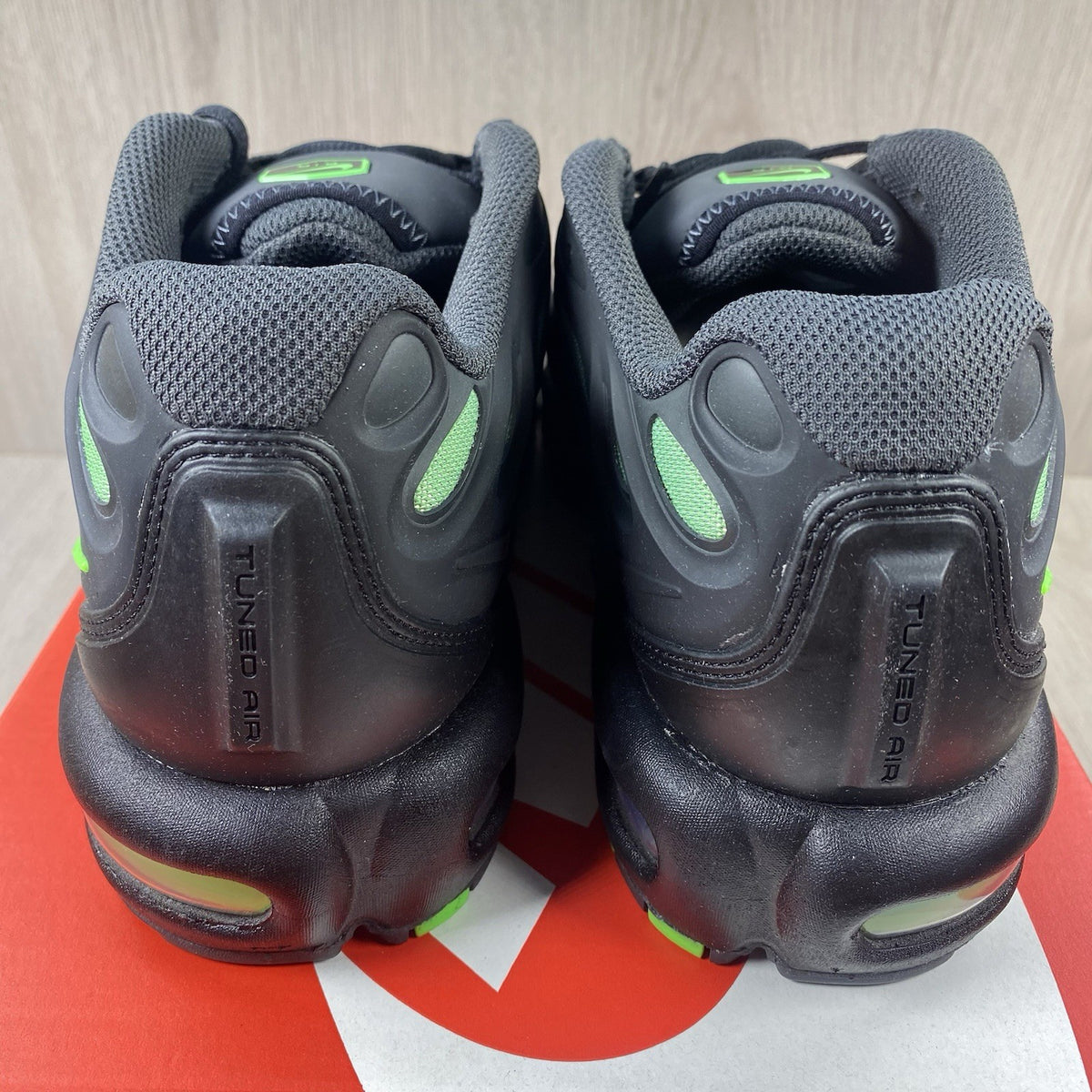 Nike Air Max Plus trainers black with volt green accents and signature swoosh logo.
