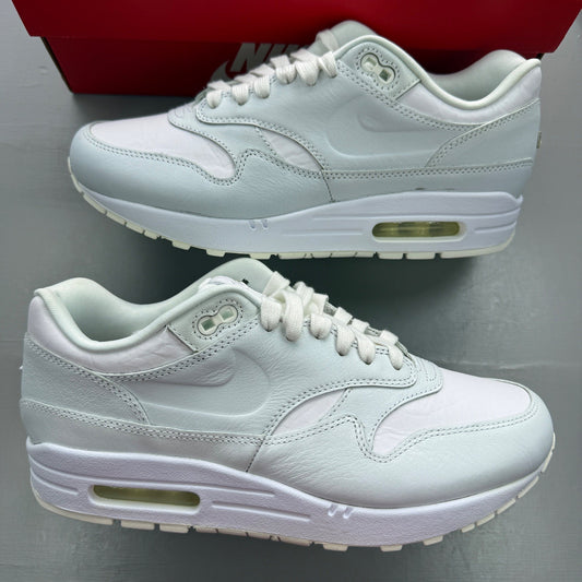 Nike Air Max 1 white trainers with rubber detailing and iconic swoosh logo.