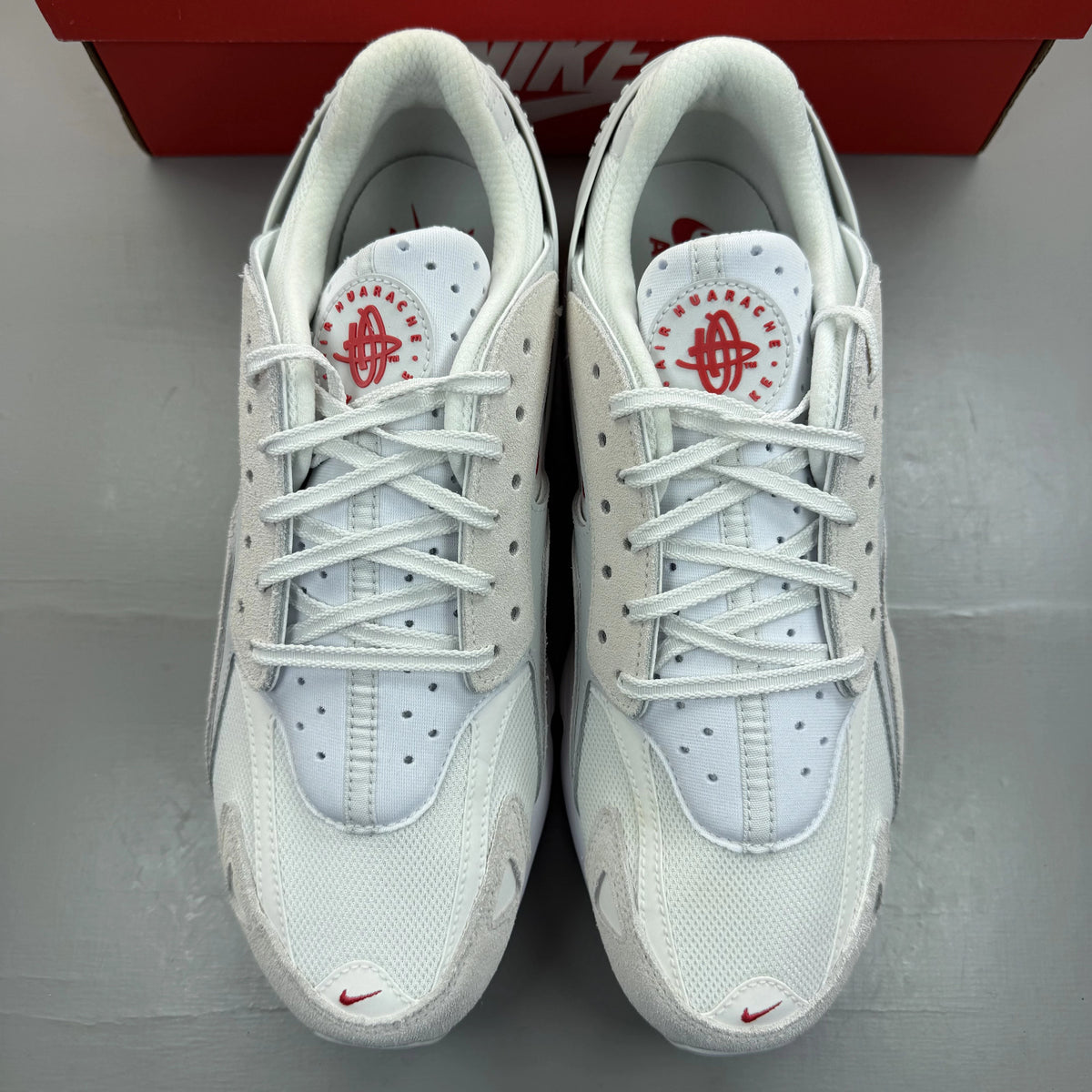 Nike Air Huarache Runner white trainers with red accents and signature logo.