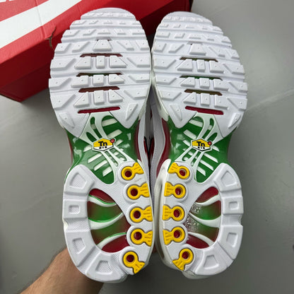 Nike Air Max Plus TN white trainers with green and red accents, featuring iconic logo.