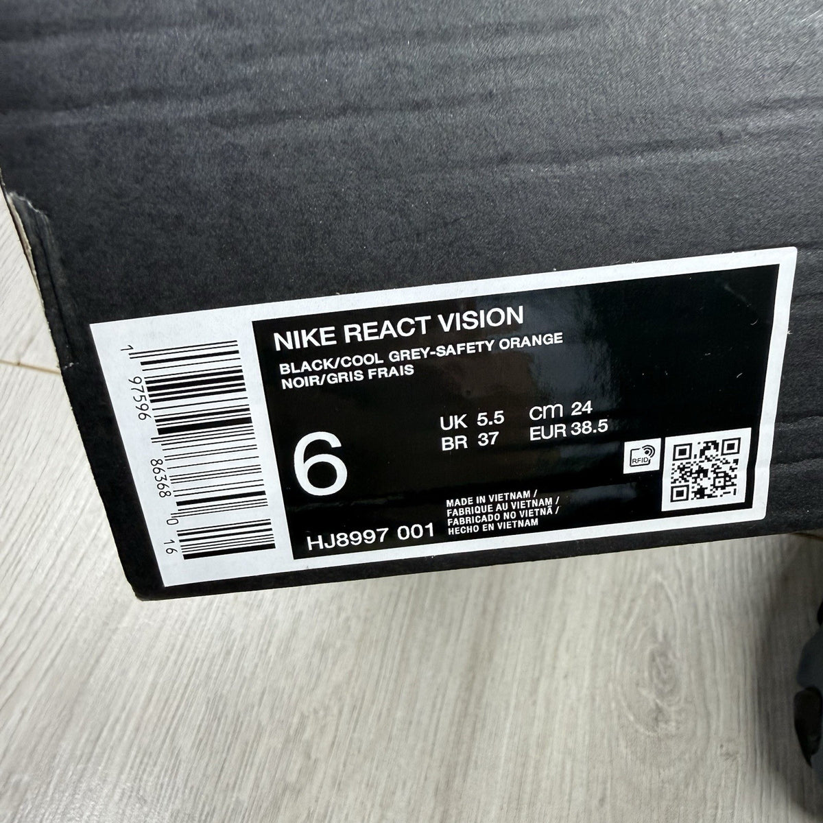 Nike React Vision black trainers with safety orange accents and unique design details.
