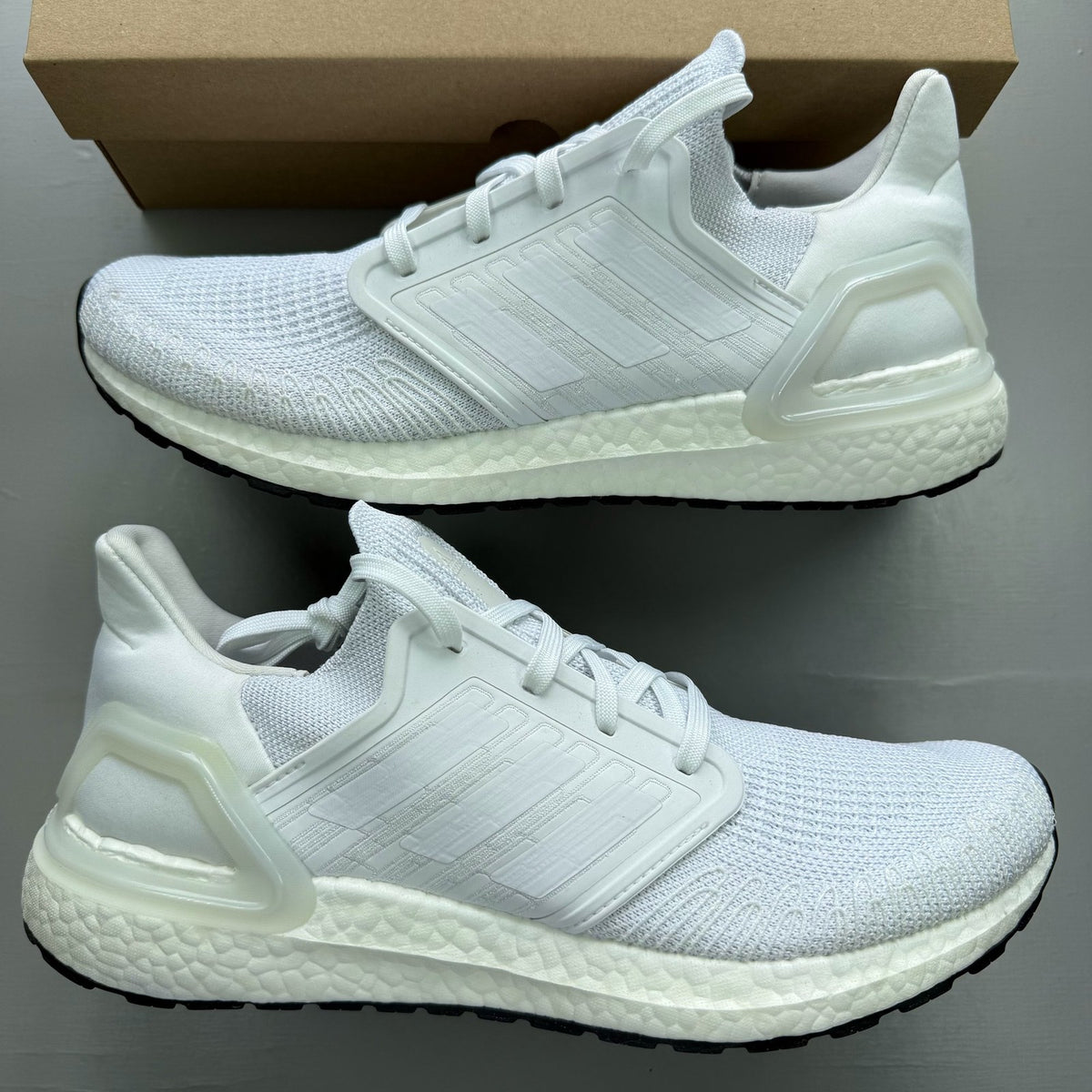 Adidas Ultra Boost 20 white running trainers with mesh upper and signature three stripes.