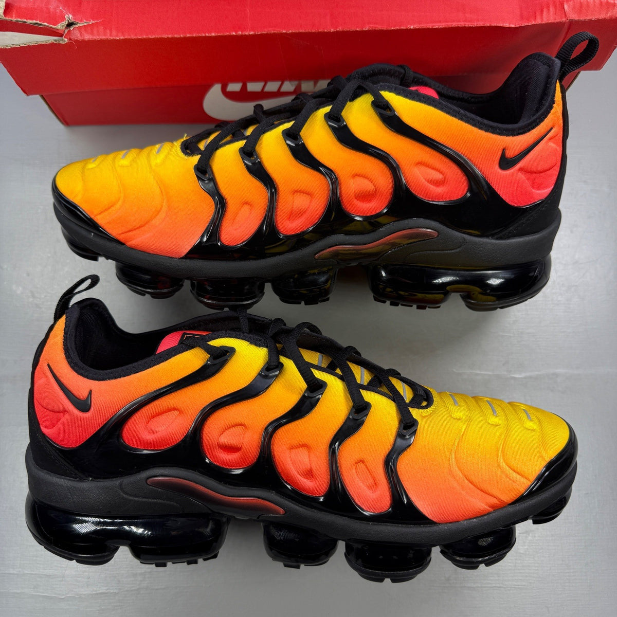 Nike athletic shoes orange with black accents and Air VaporMax sole design.