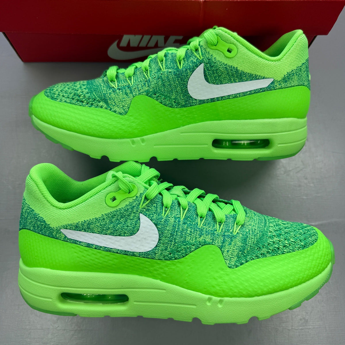 Nike trainers green Flyknit upper with Air Max cushioning and logo detail.