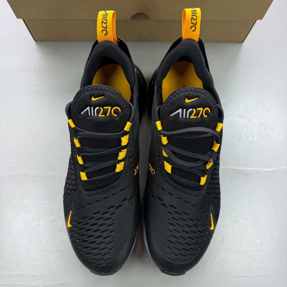 Nike black Air Max 270 trainers with grey and university gold accents, logo on tongue.