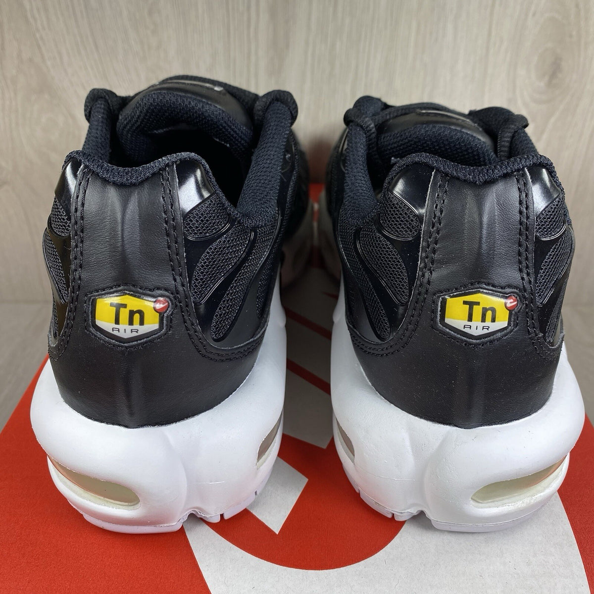 Nike Air Max Plus TN trainers black and white with signature logo and mesh detailing.